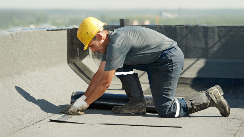 A Nashville commercial roofing professional installing a roofing system at the top of a commercial building in Nashville, TN