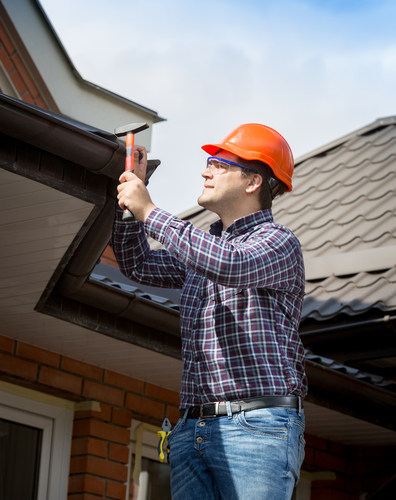 Man repairing roof near a gutter