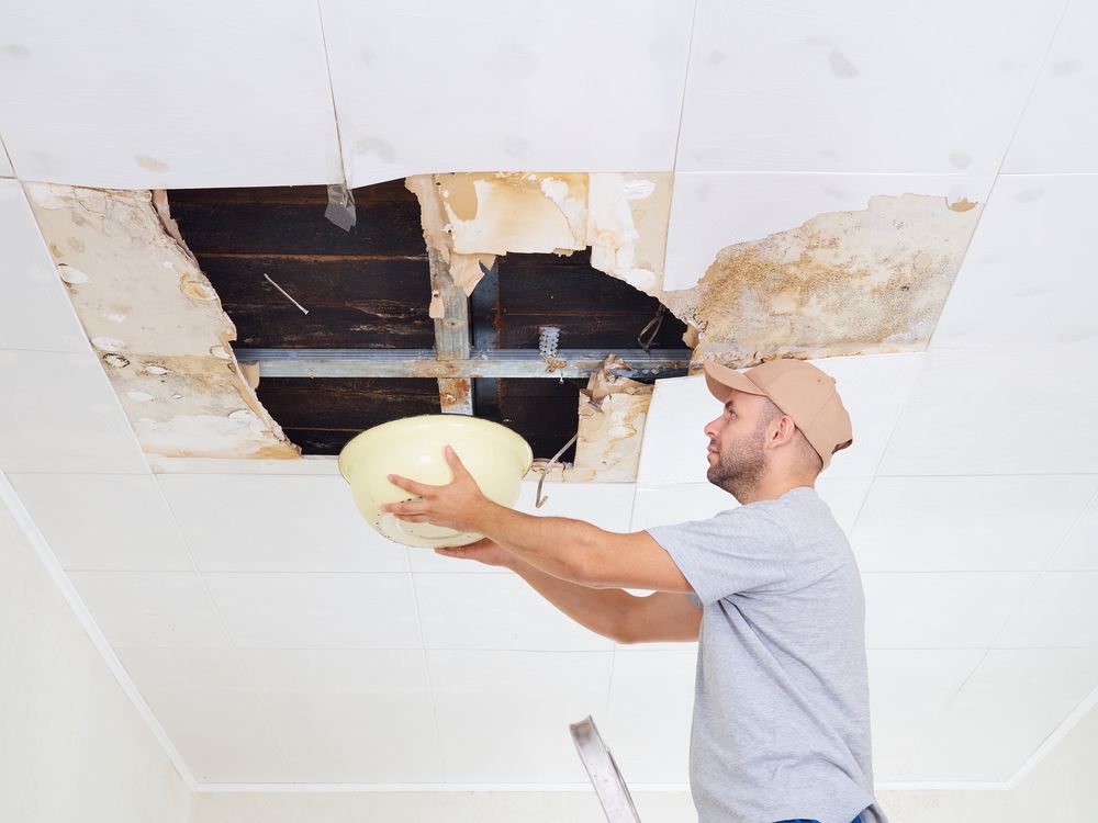 Man collecting water from a leaking roof in Nashville, TN