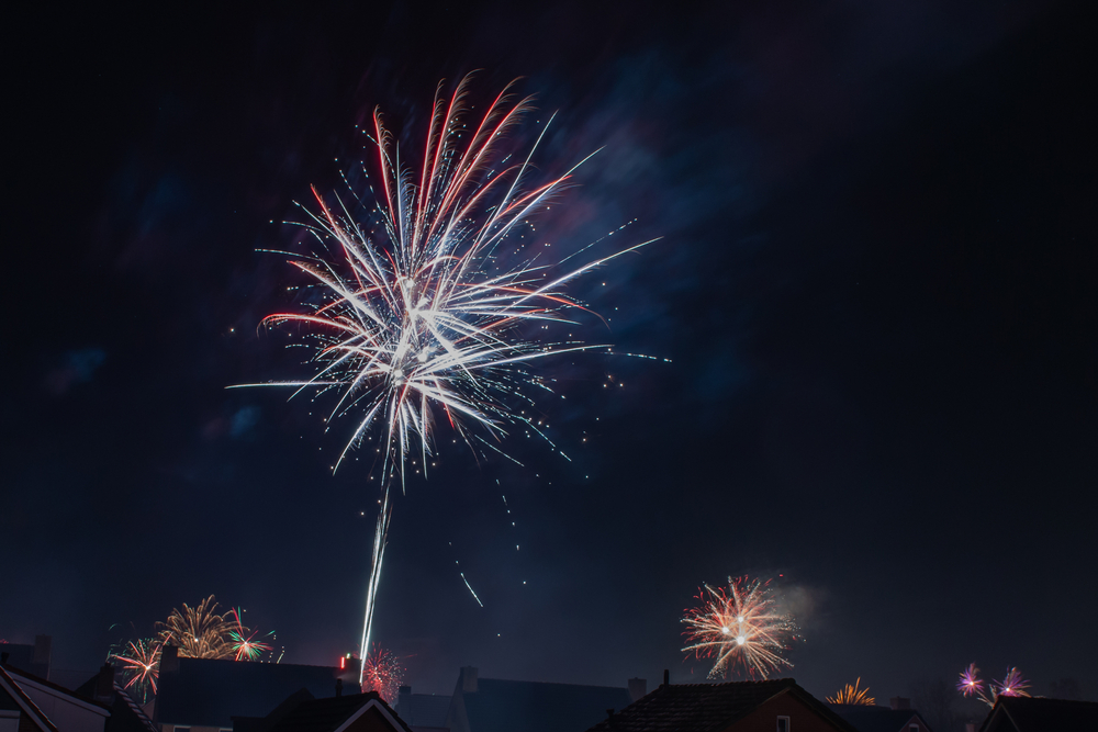 Fireworks over residential housing at night.